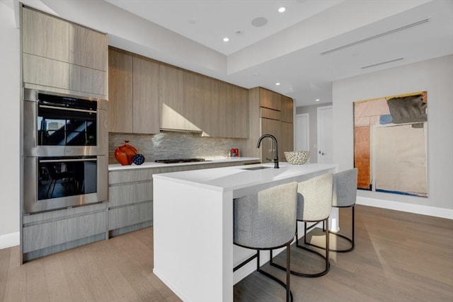 kitchen featuring light countertops, an island with sink, modern cabinets, and stainless steel appliances