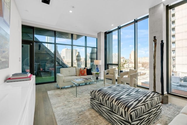 bedroom with a view of city, expansive windows, wood finished floors, and recessed lighting