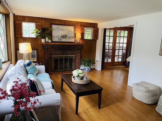 41 Sherrick Ave, Holbrook, MA 02342 - living room with a brick fireplace, wood finished floors, french doors, wooden walls, and a wall mounted air conditioner