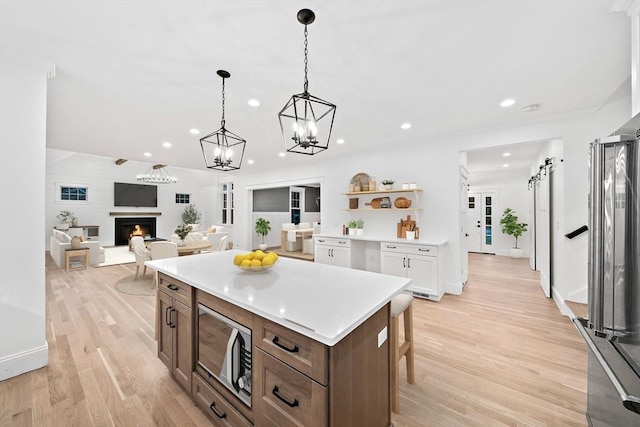 kitchen featuring a center island, hanging light fixtures, stainless steel microwave, a barn door, and white cabinets