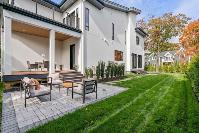 rear view of property featuring a patio, a balcony, and a lawn