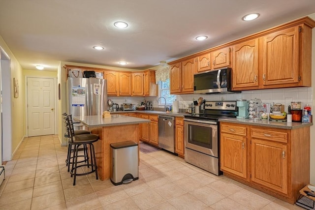 5 Rollie Shepard Dr, Millbury, MA 01527 - kitchen featuring stainless steel appliances, a breakfast bar, backsplash, a kitchen island, and brown cabinetry