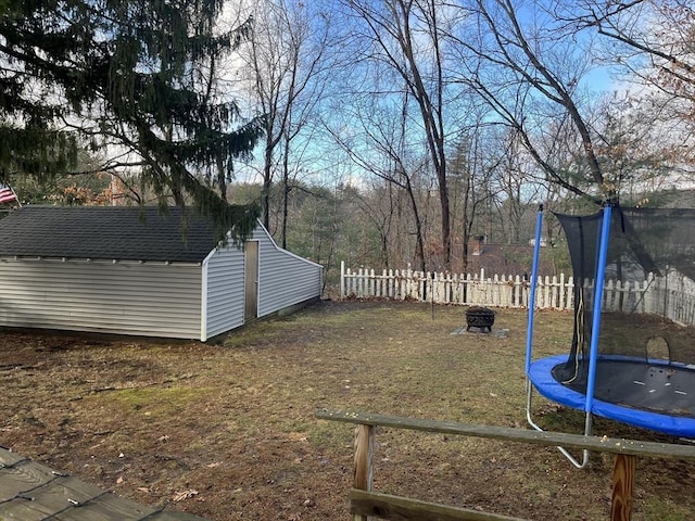 view of yard with a trampoline and a fire pit