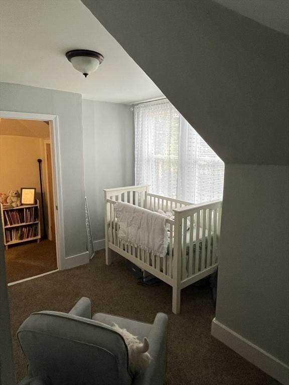 bedroom with dark colored carpet, lofted ceiling, and a nursery area