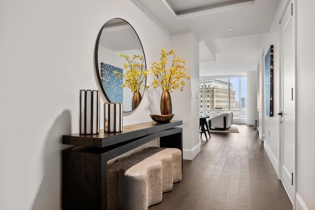 corridor featuring a view of city, baseboards, and dark wood finished floors