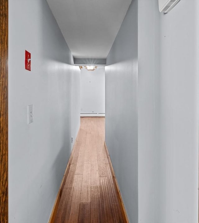 hall with baseboard heating, baseboards, and hardwood / wood-style flooring