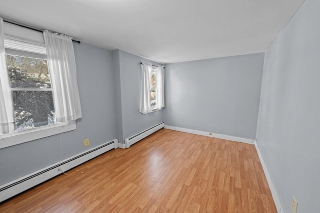 empty room with light wood-style flooring, baseboards, and baseboard heating