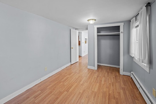 unfurnished bedroom featuring a closet, light wood-style floors, baseboards, and baseboard heating