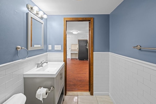 bathroom with vanity, wainscoting, tile walls, toilet, and tile patterned floors