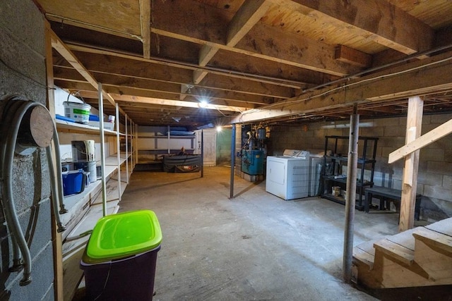 unfinished basement with washing machine and clothes dryer and concrete block wall