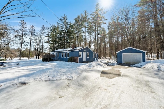 snowy yard featuring a detached garage and an outdoor structure