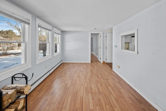 empty room featuring light wood-type flooring, baseboards, and baseboard heating