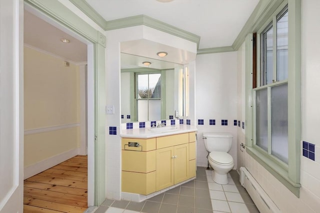 bathroom featuring vanity, hardwood / wood-style flooring, toilet, ornamental molding, and baseboard heating