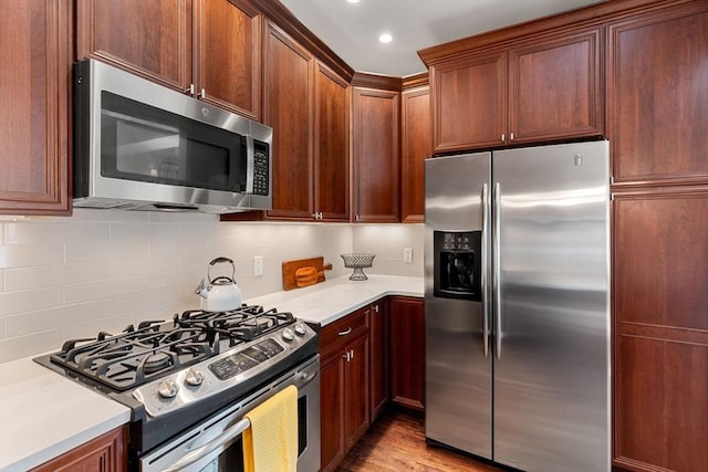 kitchen with light wood-type flooring, light countertops, decorative backsplash, and stainless steel appliances