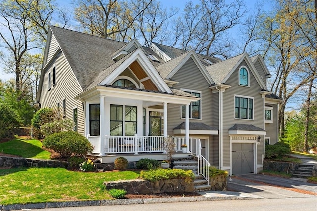 view of front facade featuring covered porch, aphalt driveway, roof with shingles, and a garage