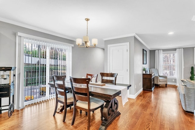 dining space featuring light hardwood / wood-style flooring, crown molding, and an inviting chandelier