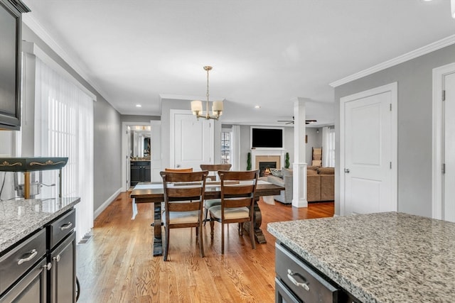 dining room featuring ceiling fan with notable chandelier, ornate columns, light hardwood / wood-style flooring, and crown molding