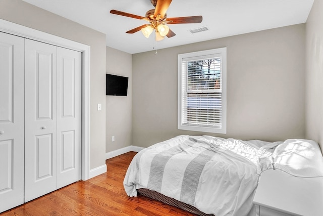 bedroom with light wood-type flooring, ceiling fan, and a closet