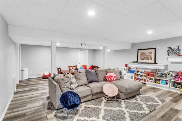 living room with a drop ceiling and wood-type flooring