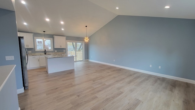 kitchen with pendant lighting, stainless steel fridge, a kitchen island, and white cabinets