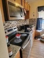 kitchen with light hardwood / wood-style floors, light stone counters, and appliances with stainless steel finishes