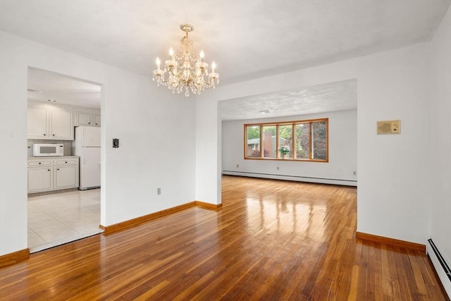 unfurnished dining area featuring a baseboard heating unit, light wood-style floors, a chandelier, and baseboards