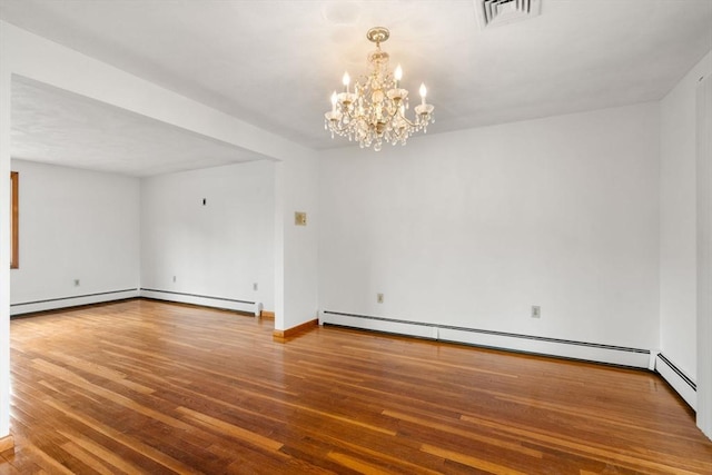 empty room featuring a chandelier, wood finished floors, baseboard heating, and baseboards