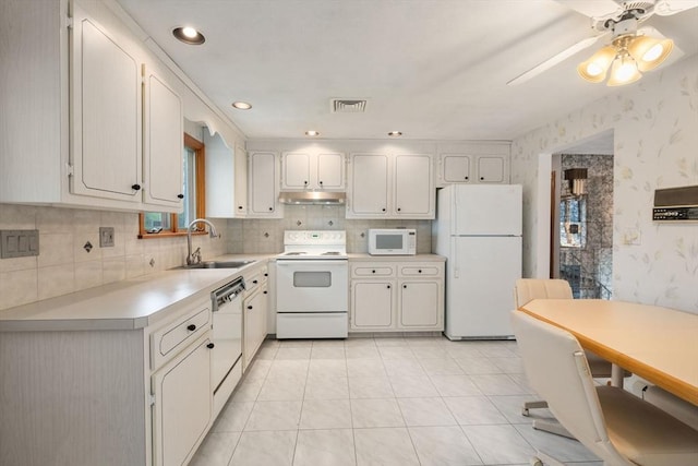 kitchen with white appliances, a sink, light countertops, wallpapered walls, and a ceiling fan