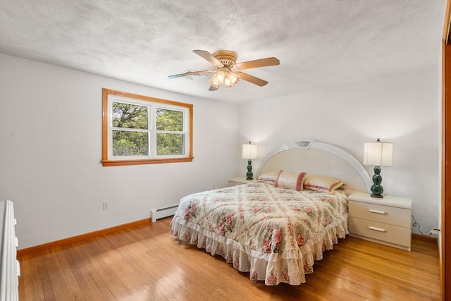 bedroom with baseboard heating, baseboards, light wood-style floors, ceiling fan, and a textured ceiling