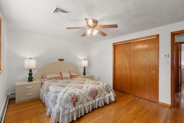 bedroom with baseboard heating, a closet, light wood-style flooring, a ceiling fan, and baseboards