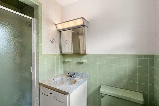 full bathroom with tile walls, a shower stall, vanity, toilet, and a wainscoted wall