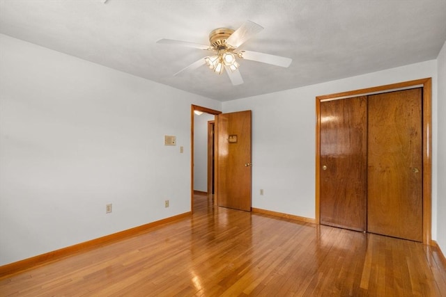 unfurnished bedroom featuring wood finished floors, baseboards, a closet, and a ceiling fan