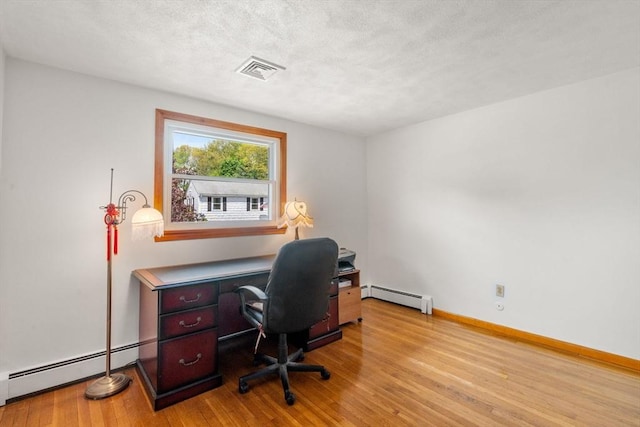 home office featuring a baseboard heating unit, light wood-type flooring, a textured ceiling, and baseboards