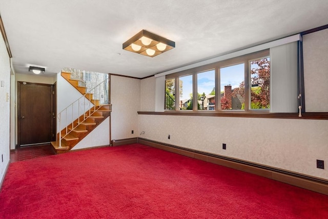 below grade area featuring dark carpet, baseboard heating, stairs, and baseboards