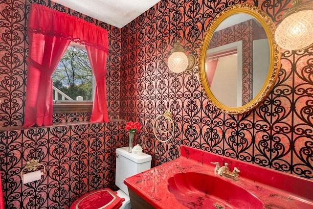 half bath with wallpapered walls, toilet, tile walls, and vanity