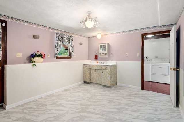 spare room with light marble finish flooring, separate washer and dryer, and a textured ceiling