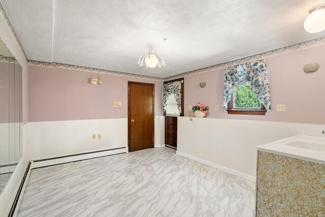 unfurnished room featuring marble finish flooring, a textured ceiling, a sink, and a baseboard heating unit