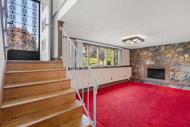 staircase with a fireplace, carpet, and baseboard heating