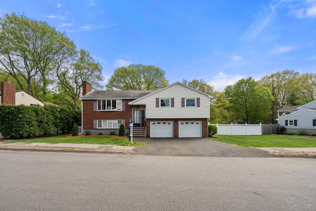 bi-level home with driveway, brick siding, a chimney, and a garage