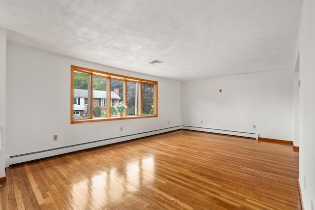 spare room with wood-type flooring, a baseboard heating unit, baseboards, and a baseboard radiator