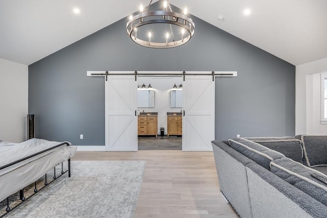 115 Kiahs Way, Sandwich, MA 02537 - bedroom with a barn door, a chandelier, light wood-style flooring, high vaulted ceiling, and connected bathroom