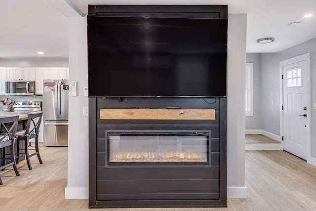 115 Kiahs Way, Sandwich, MA 02537 - detailed view of stainless steel appliances, wood finished floors, baseboards, recessed lighting, and a glass covered fireplace