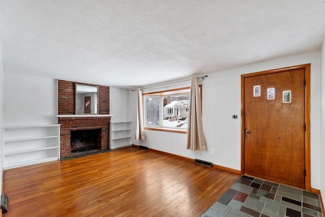 entryway featuring a textured ceiling, a fireplace, and wood-type flooring