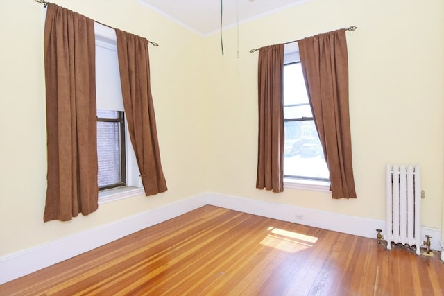 spare room featuring radiator heating unit, wood-type flooring, plenty of natural light, and crown molding