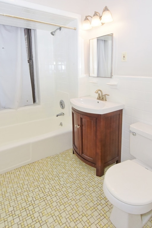 full bathroom with tile walls, toilet, vanity, tile patterned flooring, and bathtub / shower combination