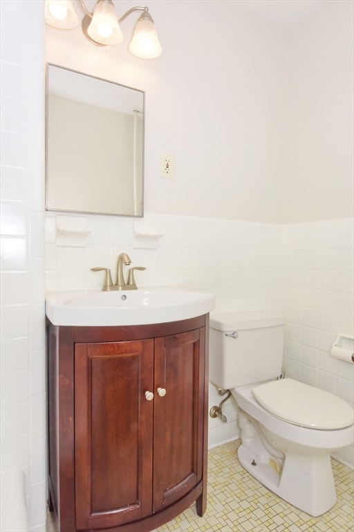 bathroom with decorative backsplash, tile walls, toilet, vanity, and tile patterned flooring