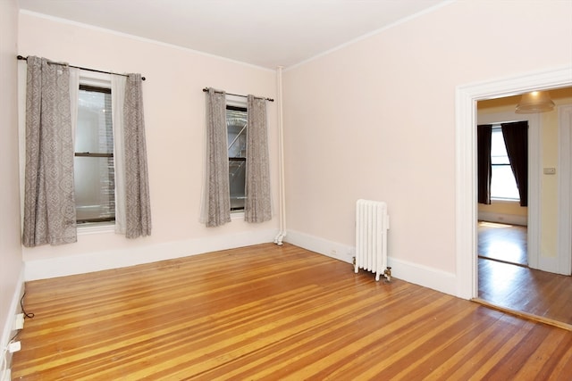 spare room featuring radiator heating unit, ornamental molding, and hardwood / wood-style floors