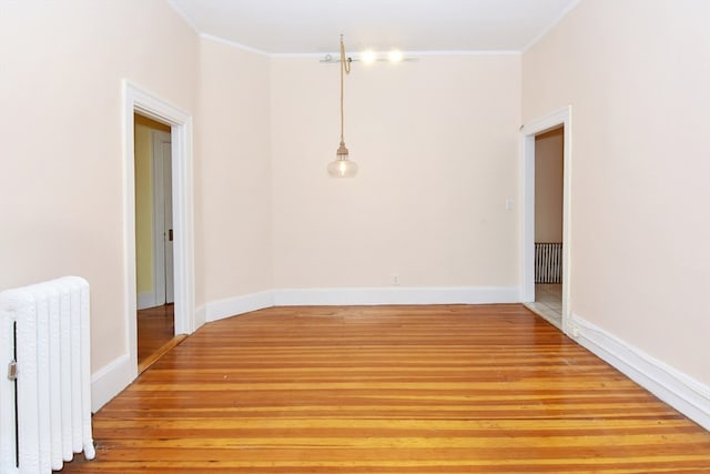 unfurnished room featuring light hardwood / wood-style flooring, radiator heating unit, and ornamental molding