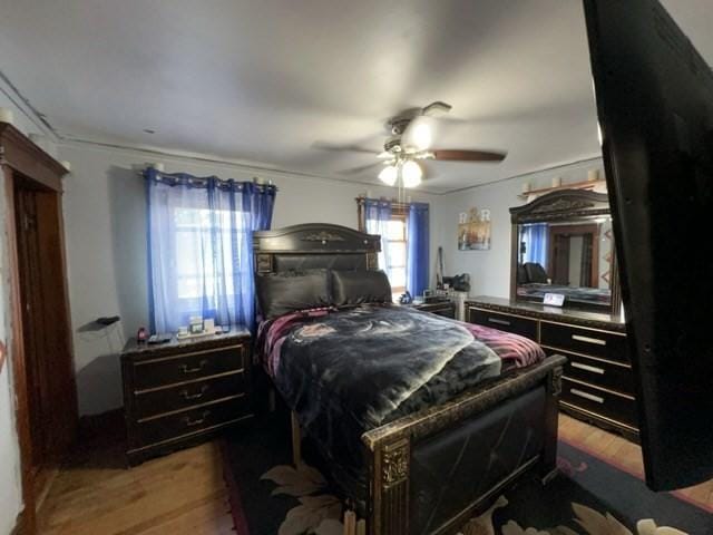 bedroom with crown molding, a ceiling fan, and wood finished floors