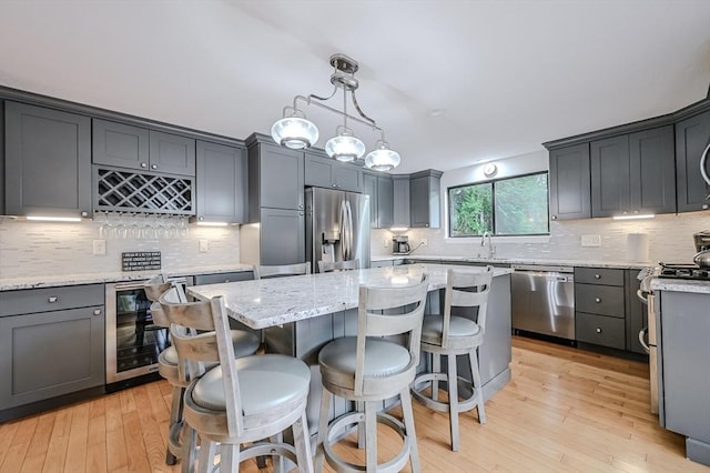 9 Country Club Ln Unit A, Milford, MA 01757 - kitchen with stainless steel appliances, beverage cooler, a kitchen island, and tasteful backsplash